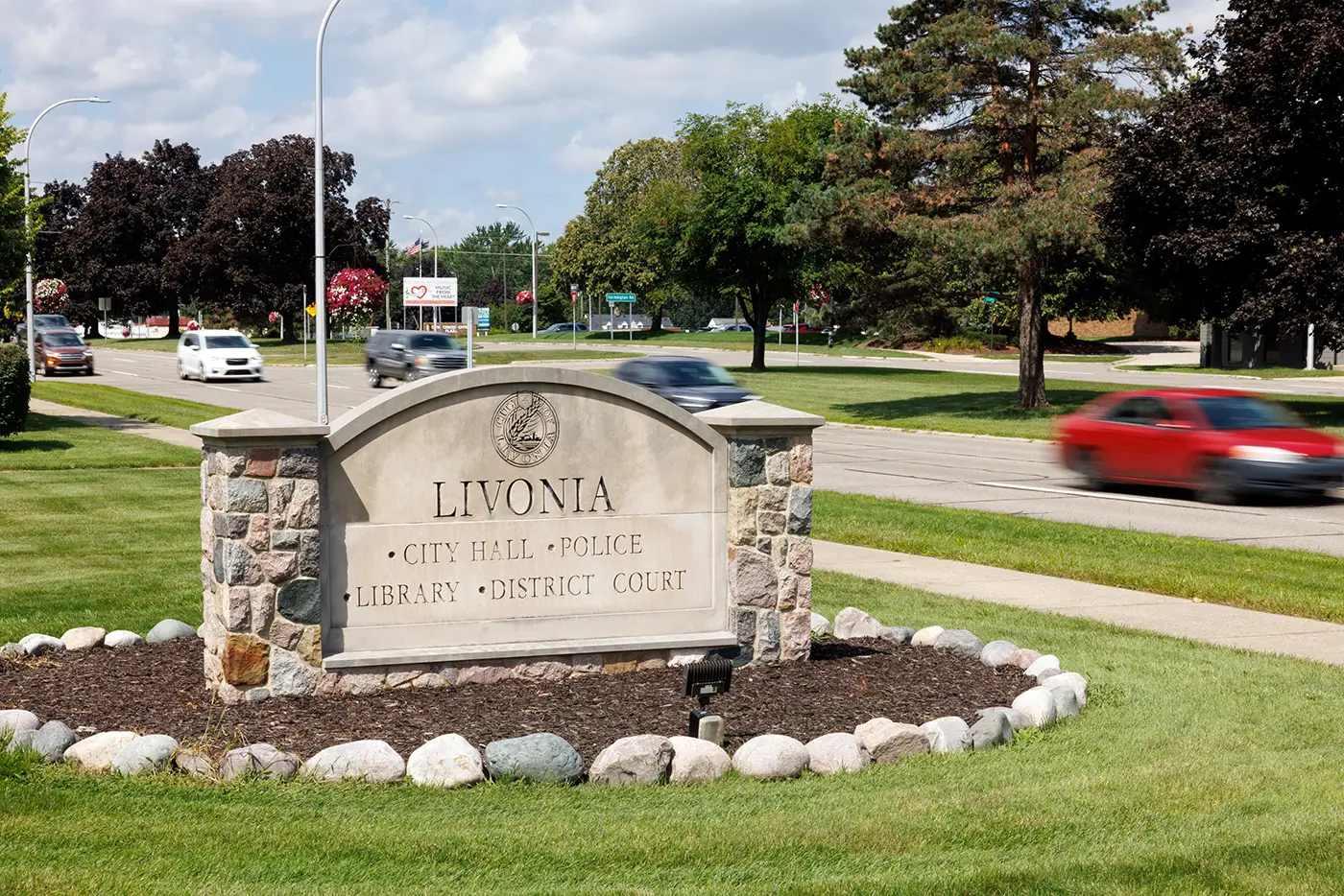 A Livonia city sign stands near moving traffic, showing the kind of roadway a car accident attorney in Livonia may deal with after a crash.