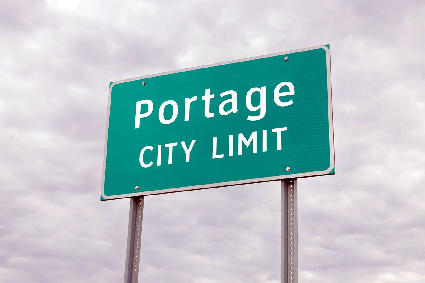 Portage city limit sign standing beneath an overcast sky, where Michigan Auto Law handles car accident cases.
