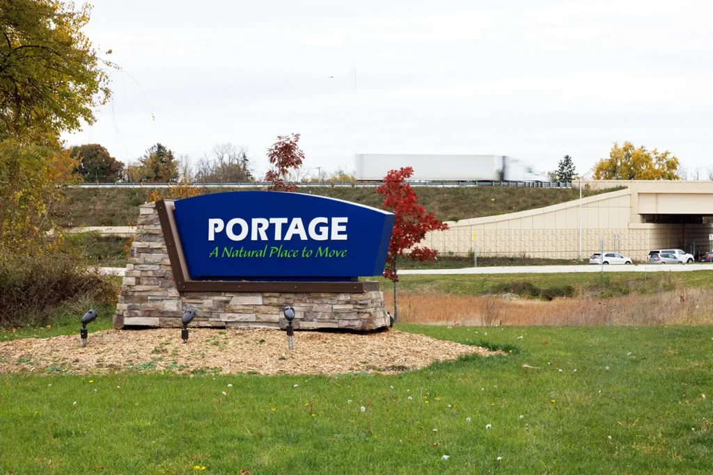 Sign for Portage, Michigan with a semi-truck traveling in the background, highlighting the community served by a Portage truck accident law firm.