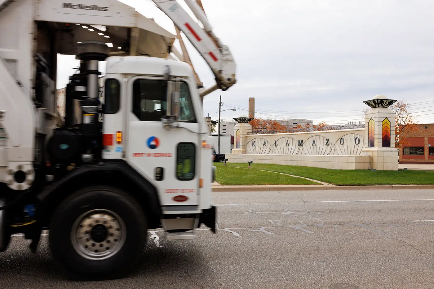 The Kalamazoo sign appears in the background as a utility truck drives by, showing a local traffic scene for a truck accident lawyer in Kalamazoo.