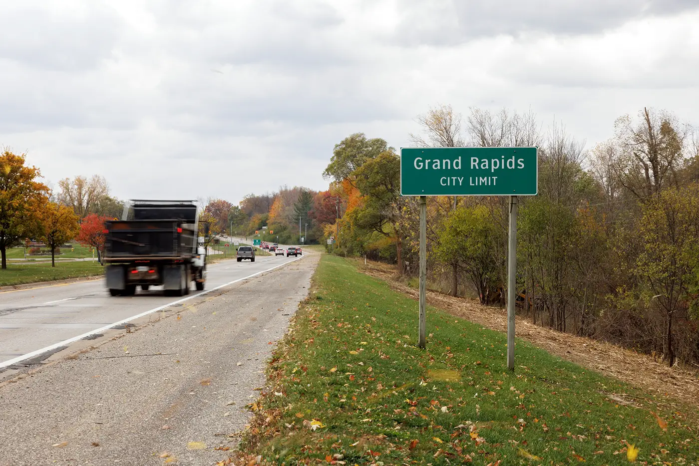 A truck passing Grand Rapids city limits sign, showing the kinds of roads truck accident lawyers in Grand Rapids deal with in serious crashes.