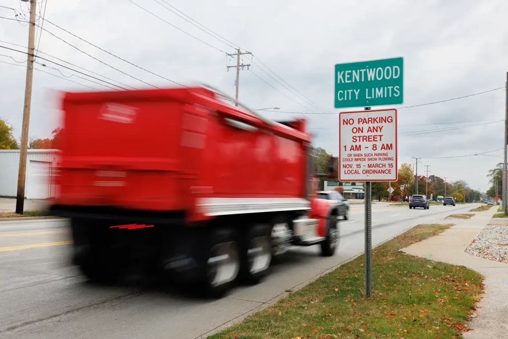 A red truck passes the Kentwood city limits sign on a local roadway, a familiar scene for a truck crash lawyer in Kentwood.