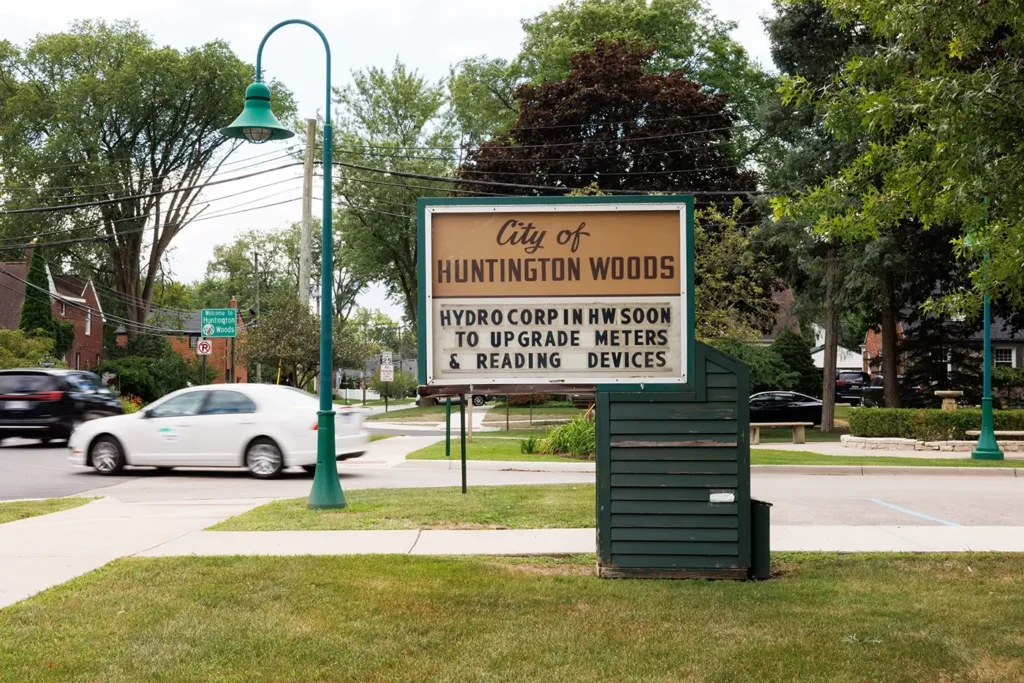 Traffic passes a Huntington Woods city sign where Michigan Auto Law car accident law provides legal services.
