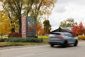 Welcome to Holland sign with passing traffic, highlighting Michigan Auto Law as a Holland car accident lawyer.