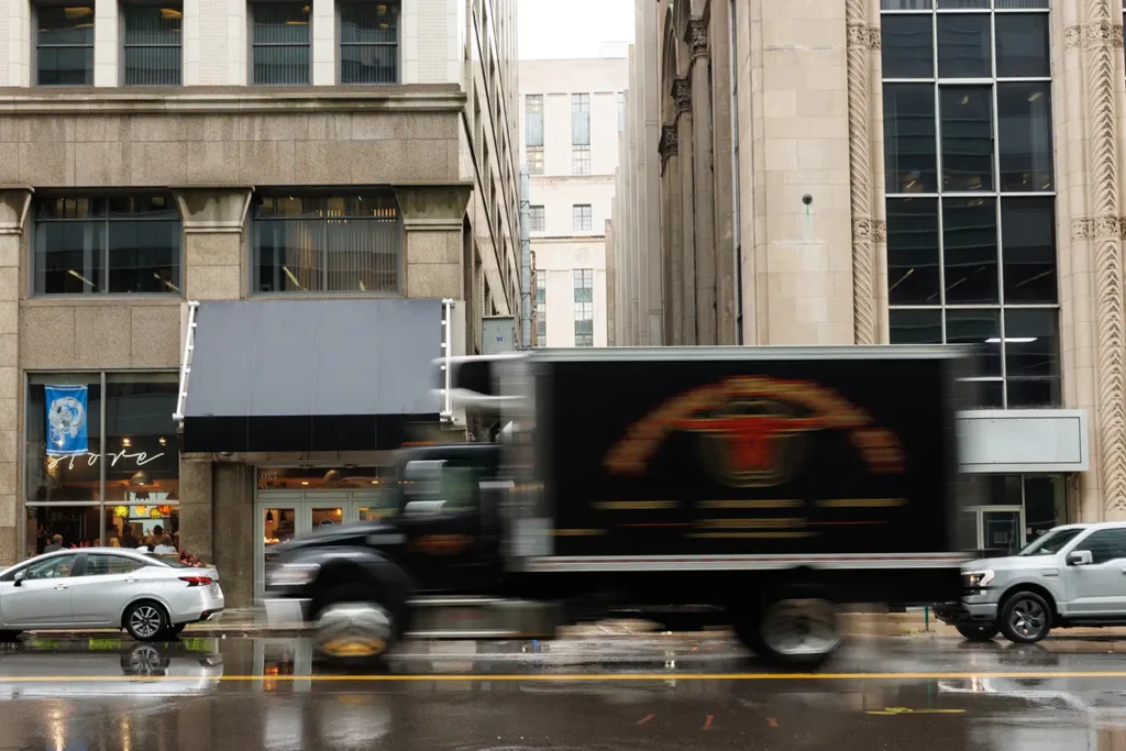A large truck passes a downtown Detroit storefront, where Michigan Auto Law helps crash victims as a Detroit truck accident lawyer.