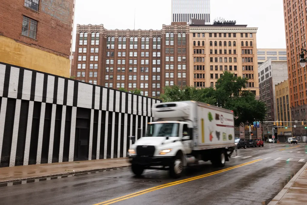A box truck drives through downtown Detroit on a wet city street, where Michigan Auto Law helps crash victims as a Detroit truck crash attorney.