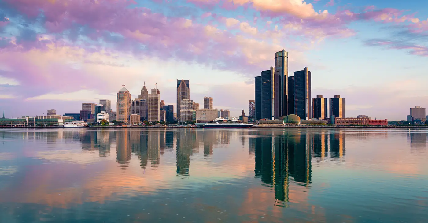 Detroit skyline over the river at sunset, representing Uber crash lawyer services in Detroit.