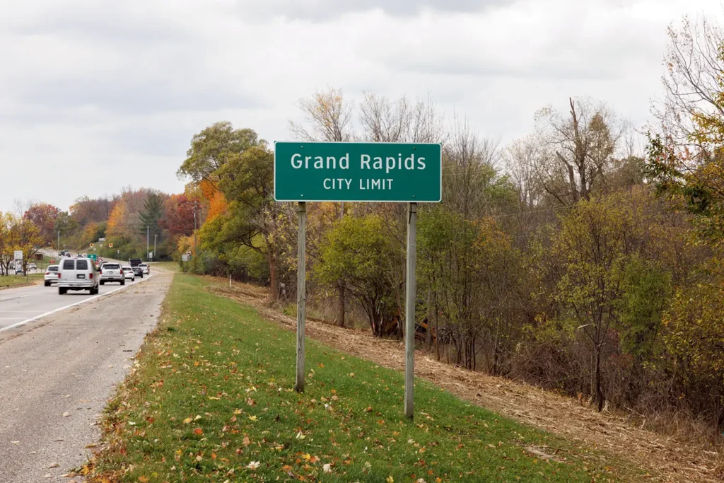 Cars travel near the Grand Rapids city limit sign on a roadway served by a Lyft accident lawyer in Grand Rapids. 