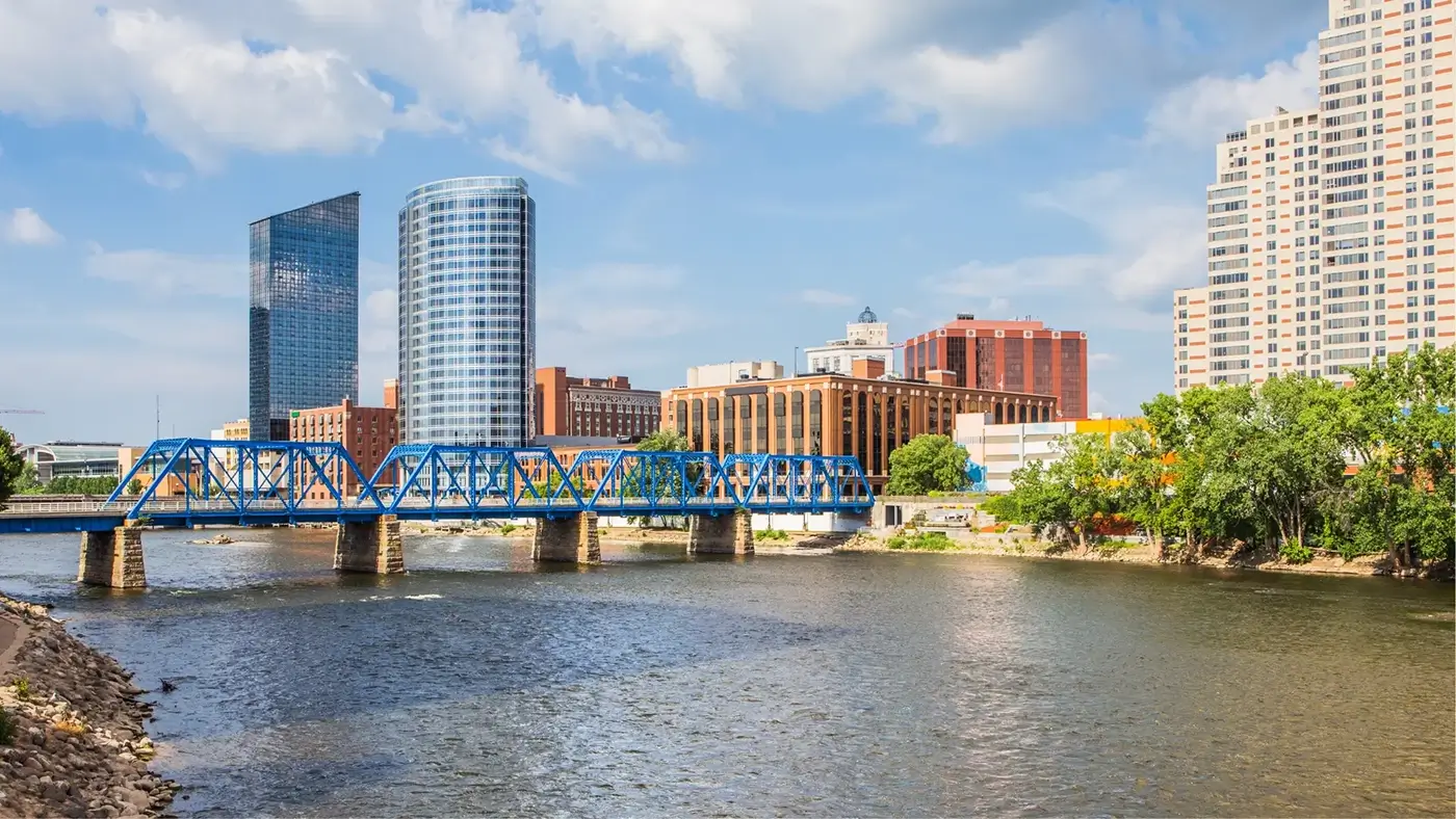 Blue bridge and Grand Rapids skyline over the river, showing the area served by a motorcycle accident law firm in Grand Rapids.