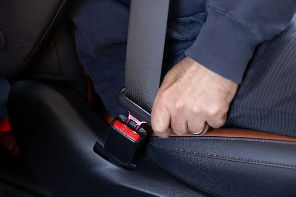 Road trip checklist reminder showing a passenger buckling their seat belt.