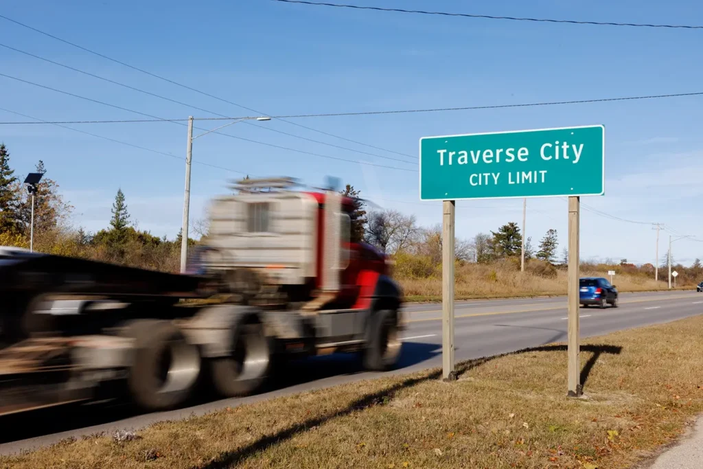 Truck moves past the Traverse City city limit sign, showing the area where Michigan Auto Law handles truck accident lawyer cases.