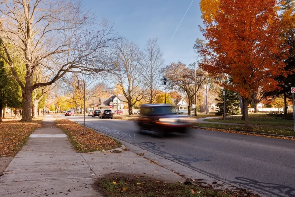Cars move along a fall residential street in Traverse City where Michigan Auto Law helps people after Uber-related accidents.