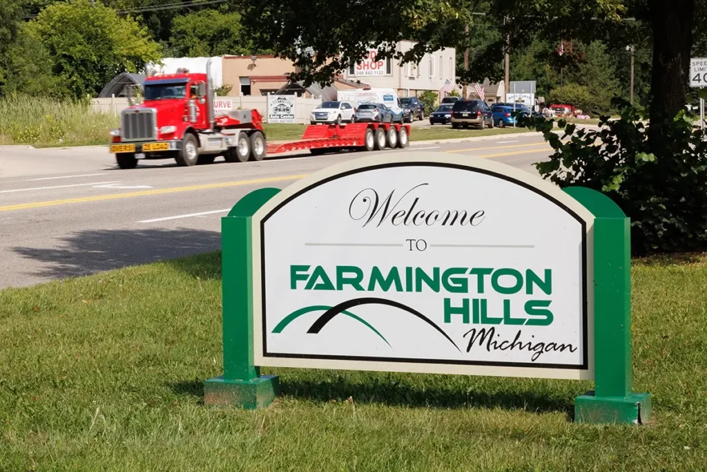 Farmington Hills welcome sign beside a roadway with a semi-truck, representing truck accident lawyer Farmington Hills services.