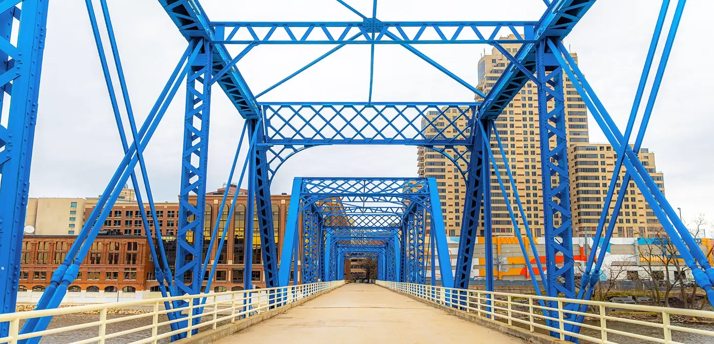 Blue truss bridge in downtown Grand Rapids, representing the city where Michigan Auto Law provides pedestrian accident attorney services.