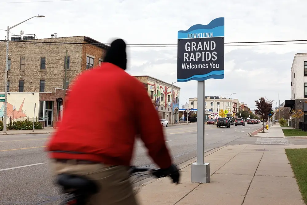 Cyclist passing a Downtown Grand Rapids welcome sign, where Michigan Auto Law provides pedestrian accident lawyer services.